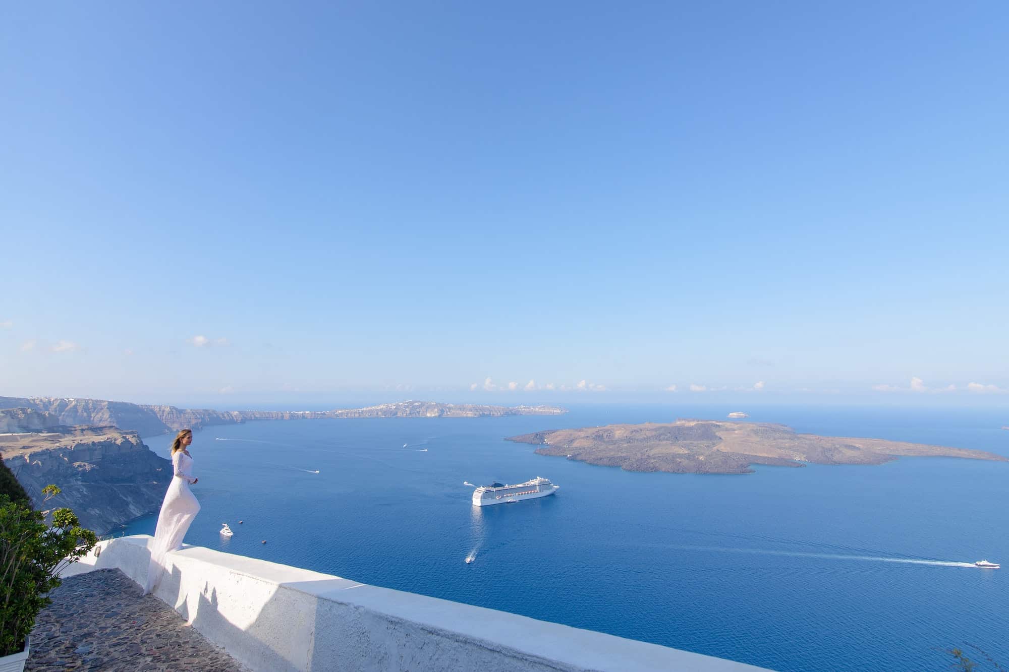 Beautiful bride In a white dress posing against the background of the Mediterranean Sea in Thira.
