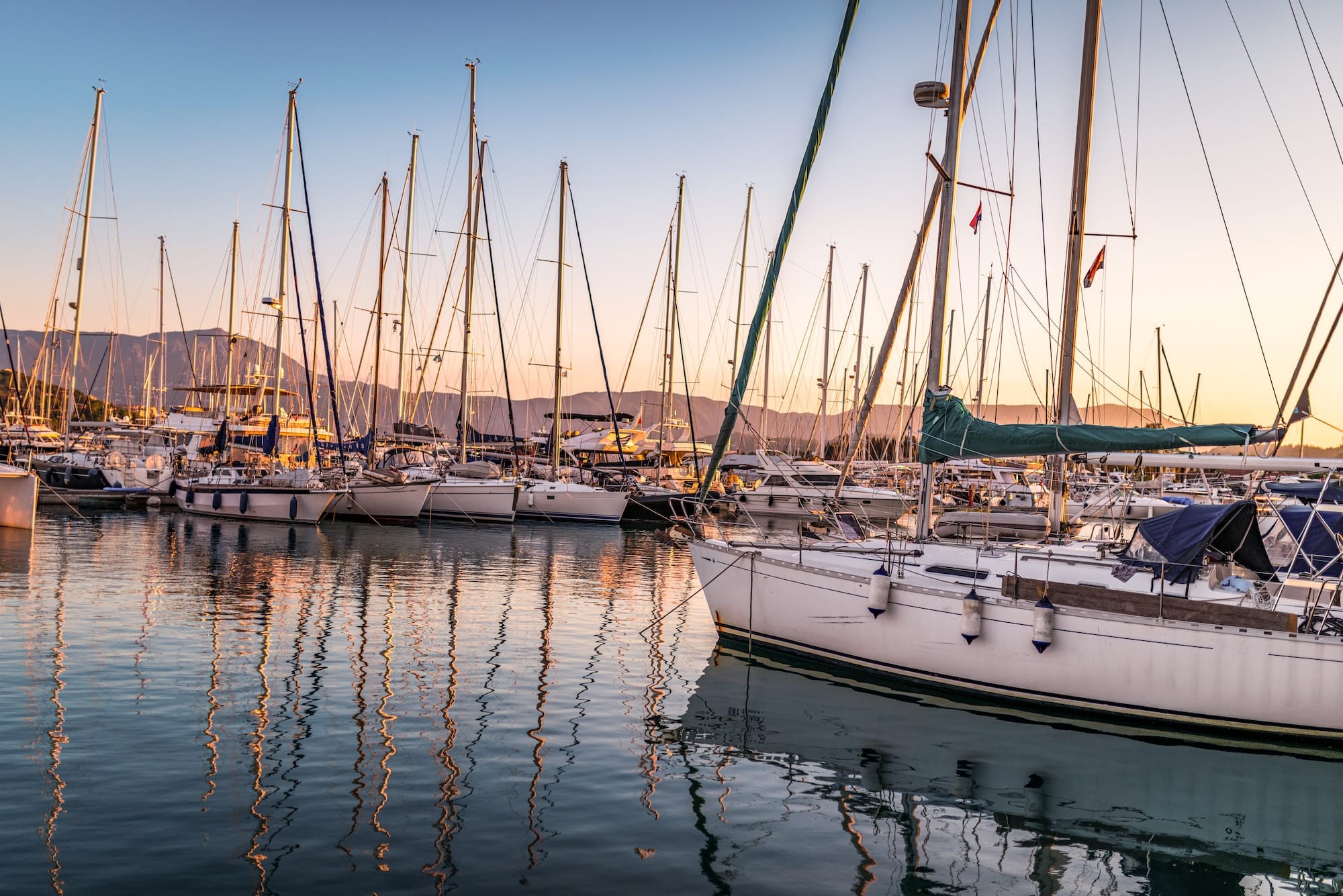 Pier with motorboats and yachts moored alongside at sunset