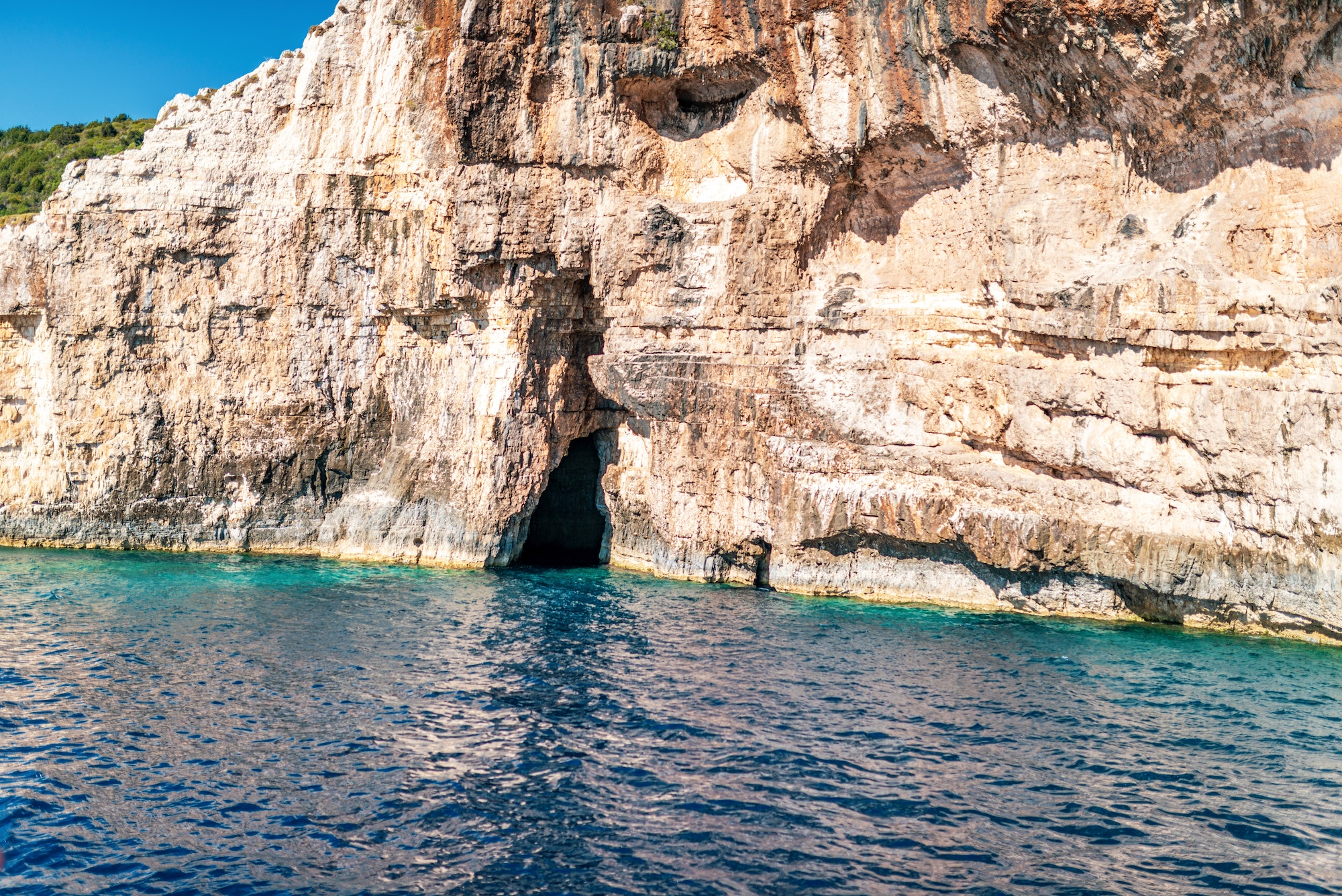 High stoned cliff on sea beach of Corfu island at sunset