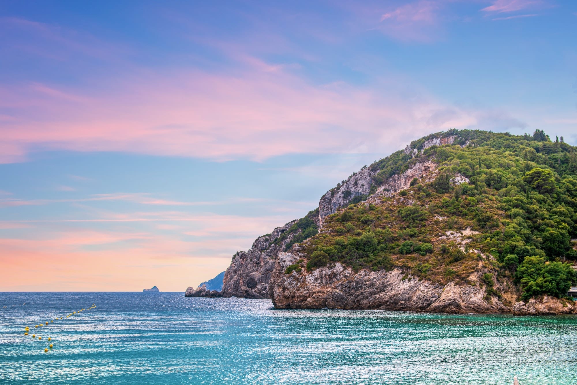 Calm beach of Mediterranean sea near high hill with forest