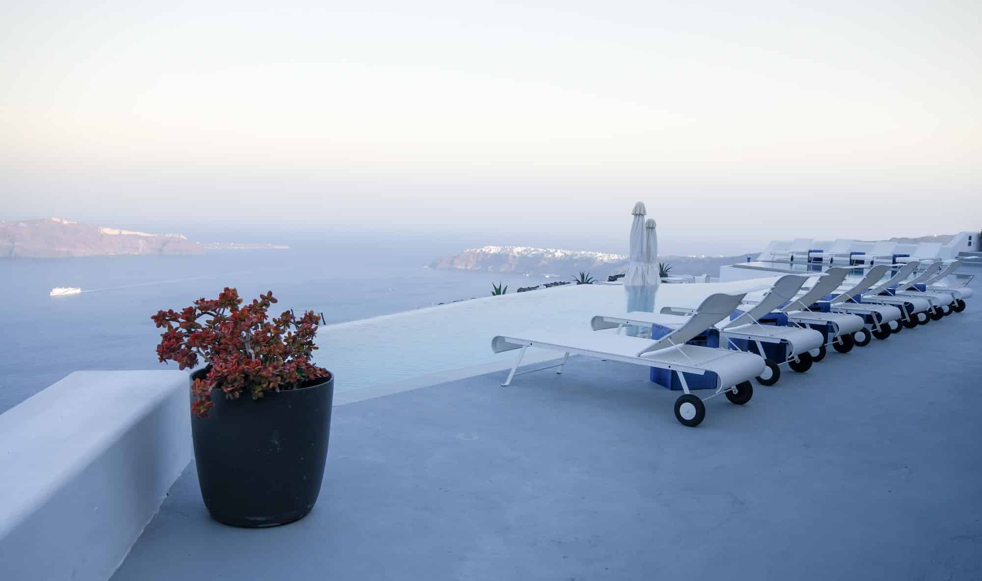 Roof garden of a holiday resort hotel against the ocean at sunset. Oia village, Santorini Island