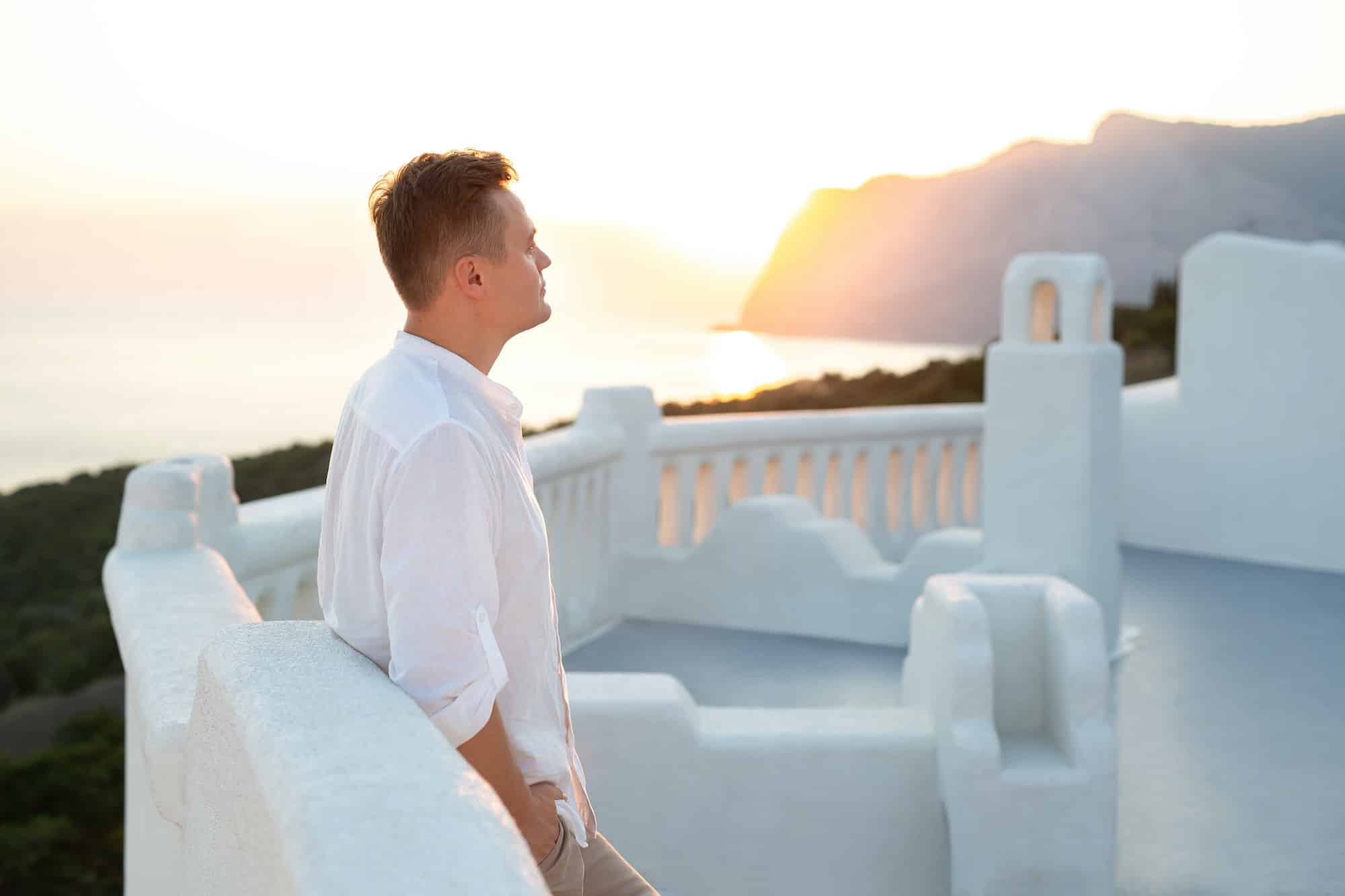 Portrait of a young man, a groom in a white shirt on the island of Santorini, Greece.