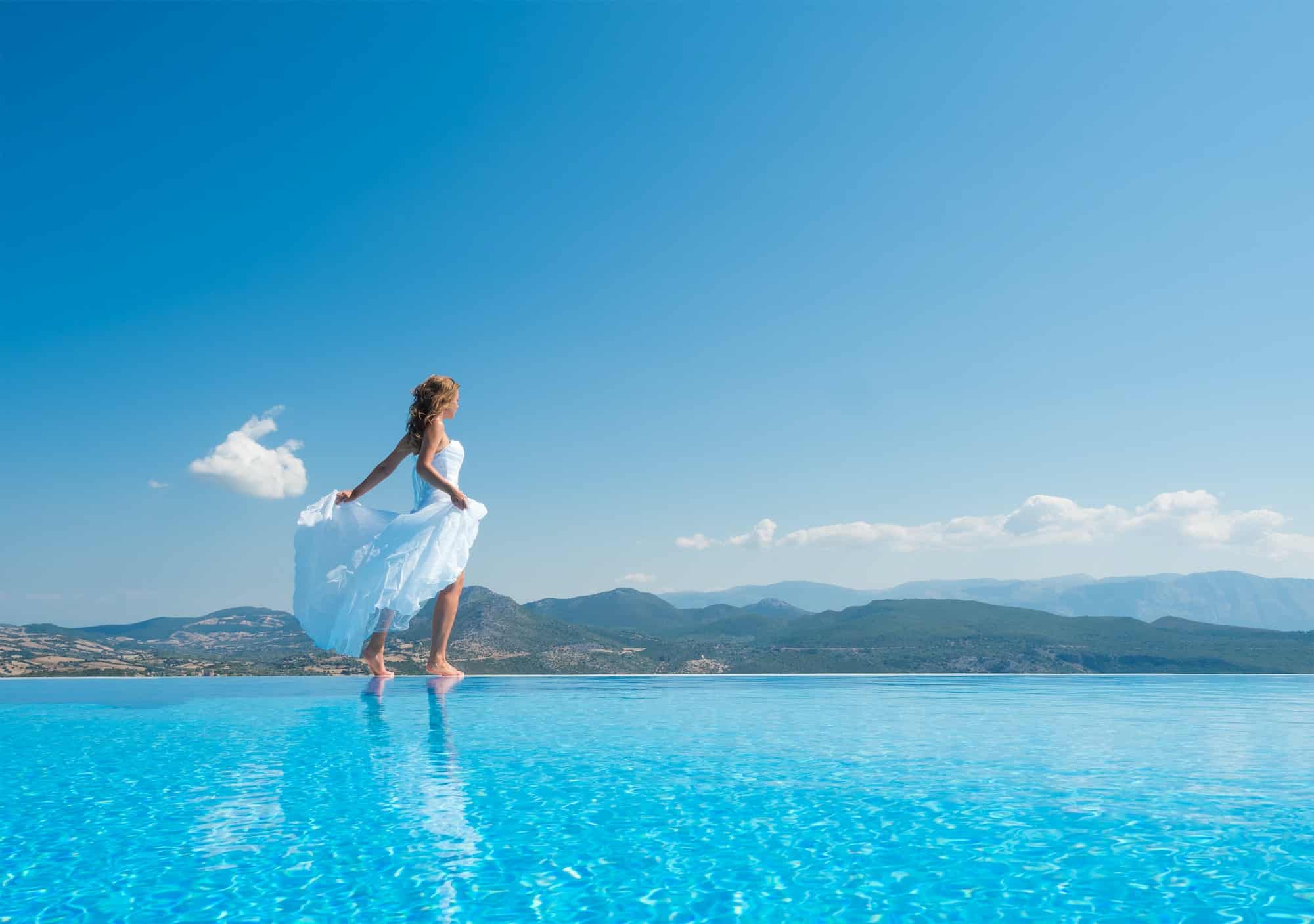 Bride standing on the edge on the infinity pool in Santorini