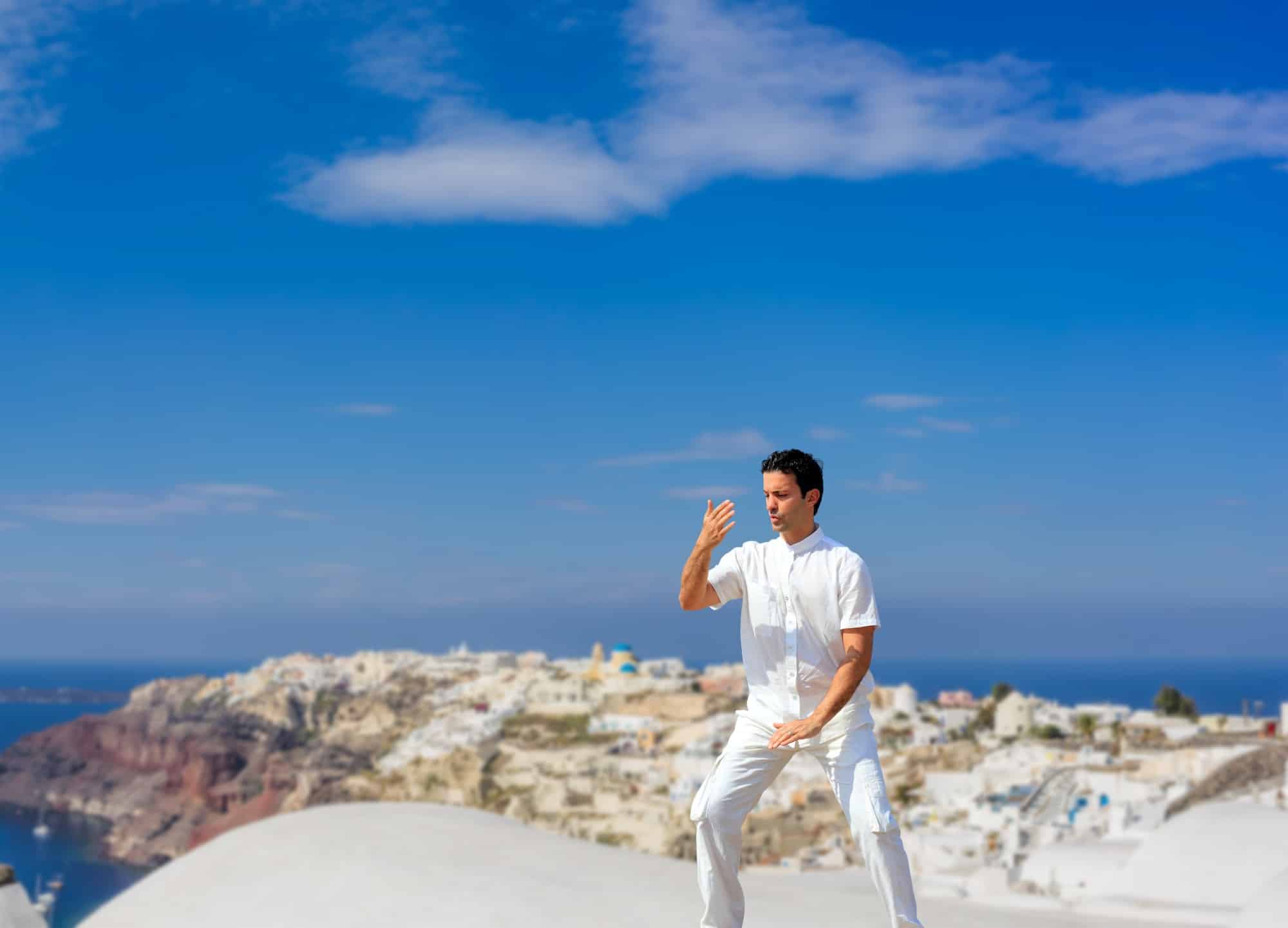 Handsome man practicing Tai Chi of the rooftops in Oia Santorini island