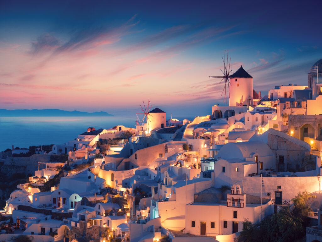 Amazing sunset view with white houses in Oia village on Santorini island in Greece.