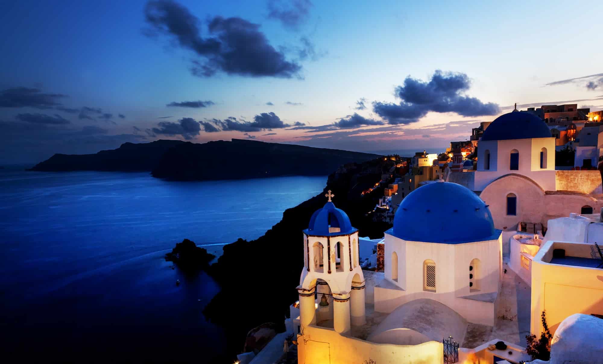 Oia town on Santorini island, Greece at night. Rocks on Aegean sea.