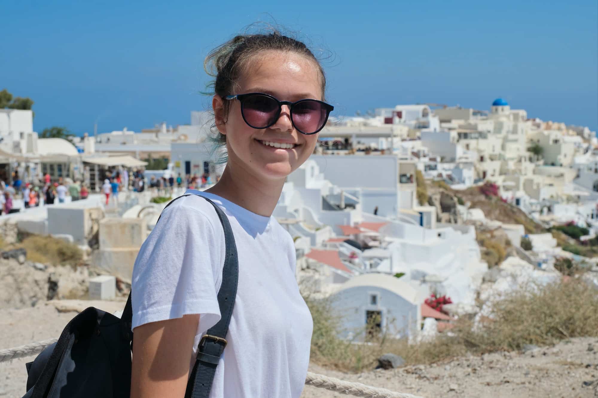 Smiling teenager posing on the island Santorini, from Oia, Greece