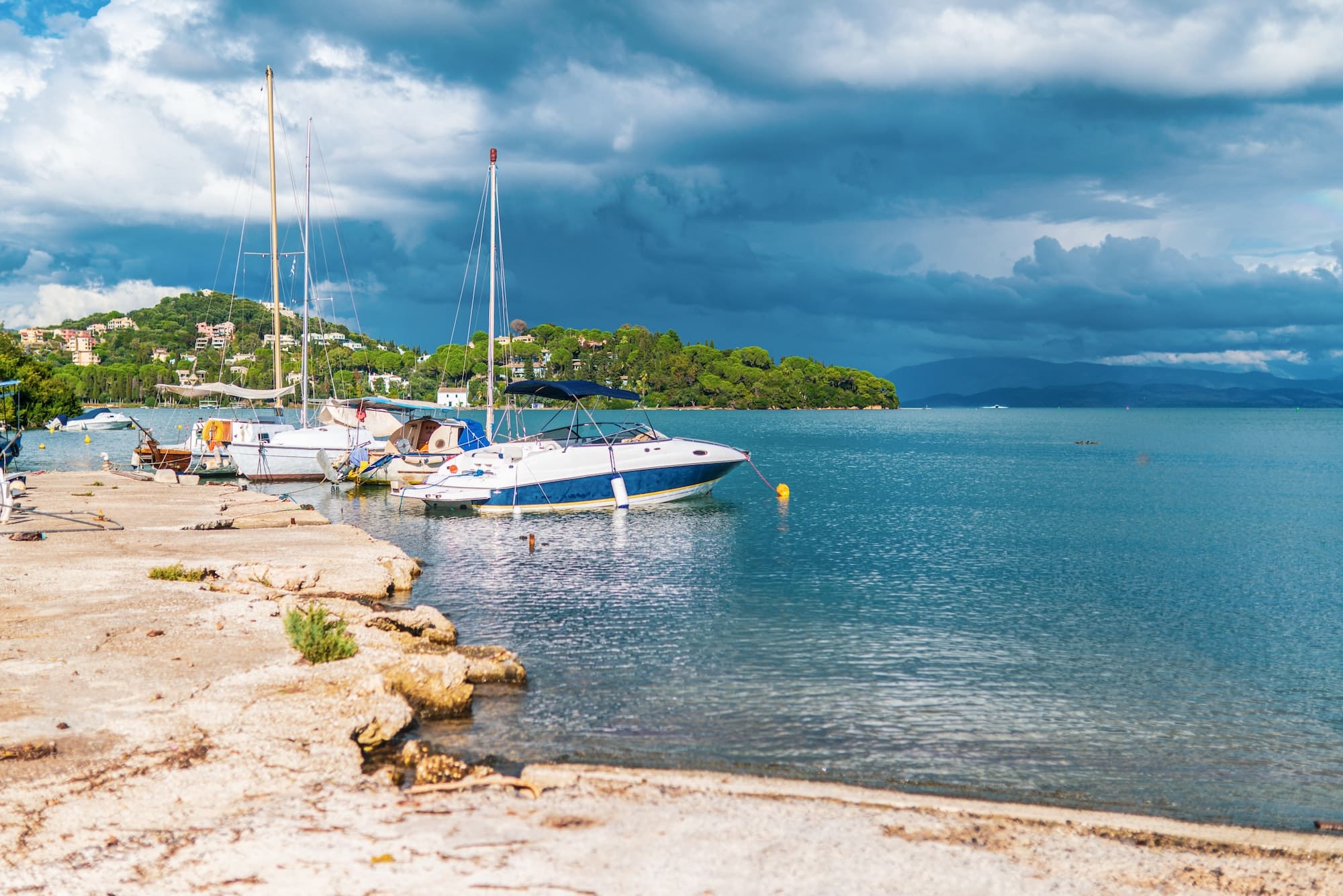 Yachts moored at Corfu island beach under grey stormy sky