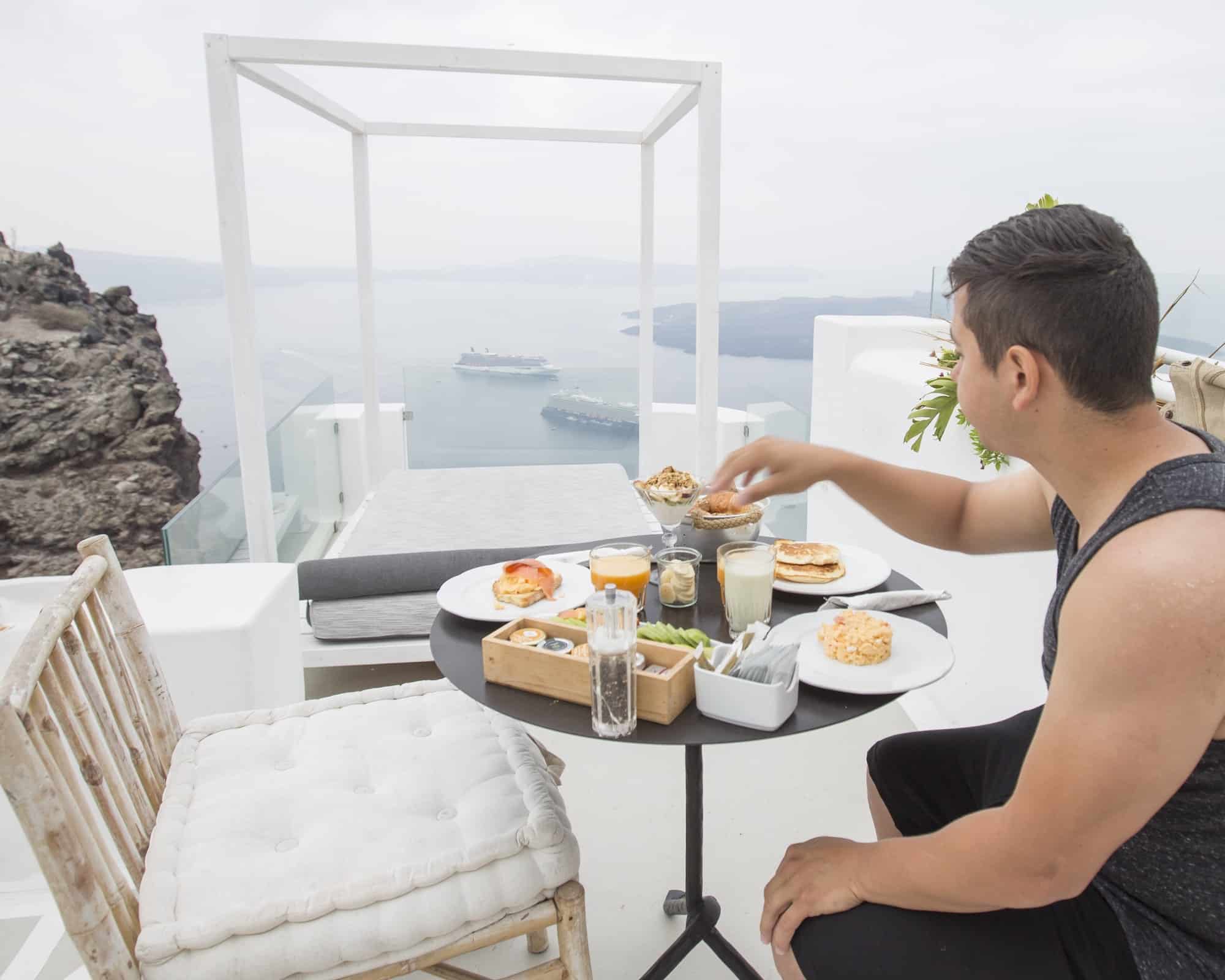 Man having brunch on a porch while on vacation in santorini Greece