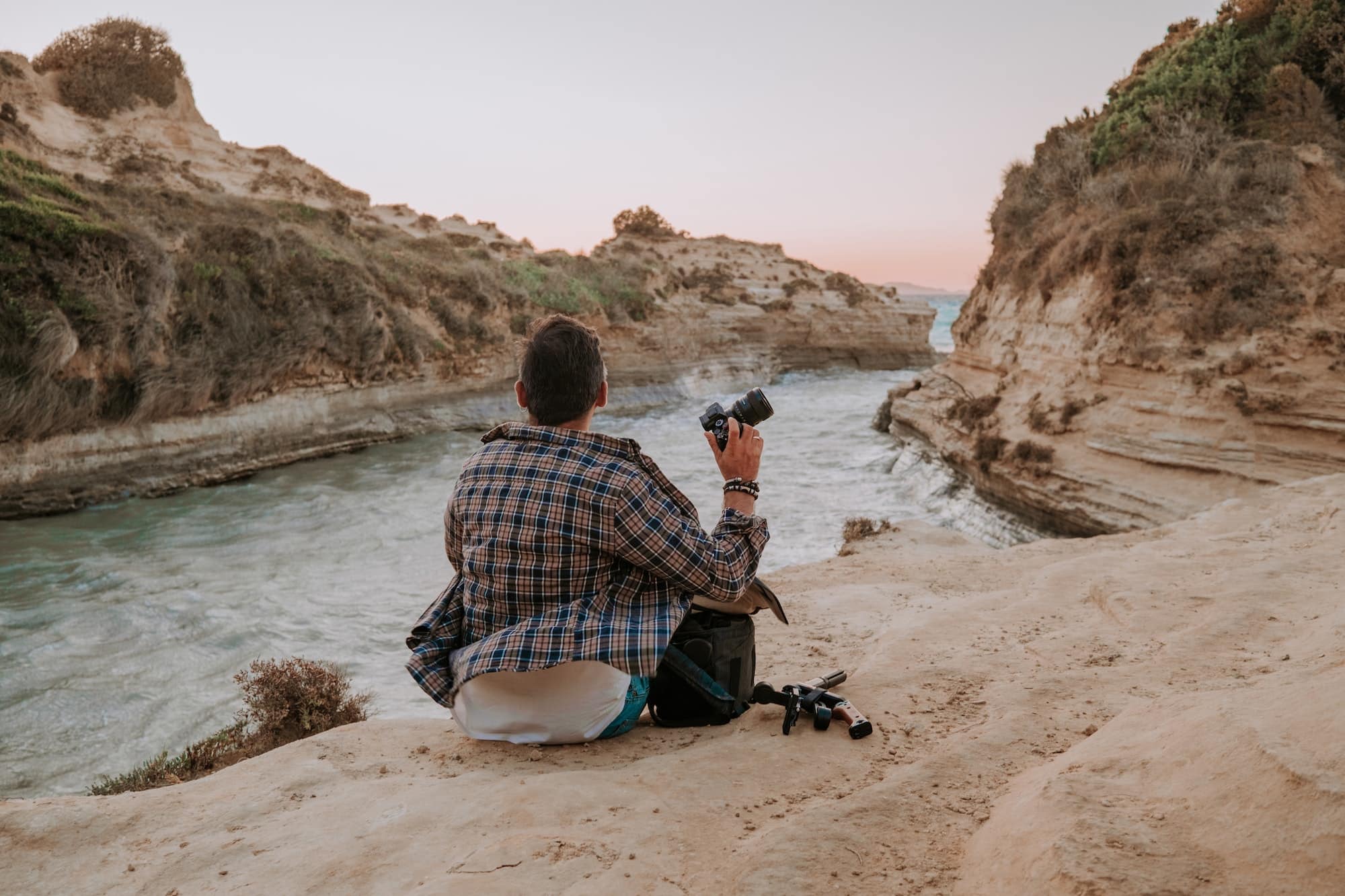 Stranger man hipster photographer sitting on seashore near love channel - Canal D'Amour on Corfu