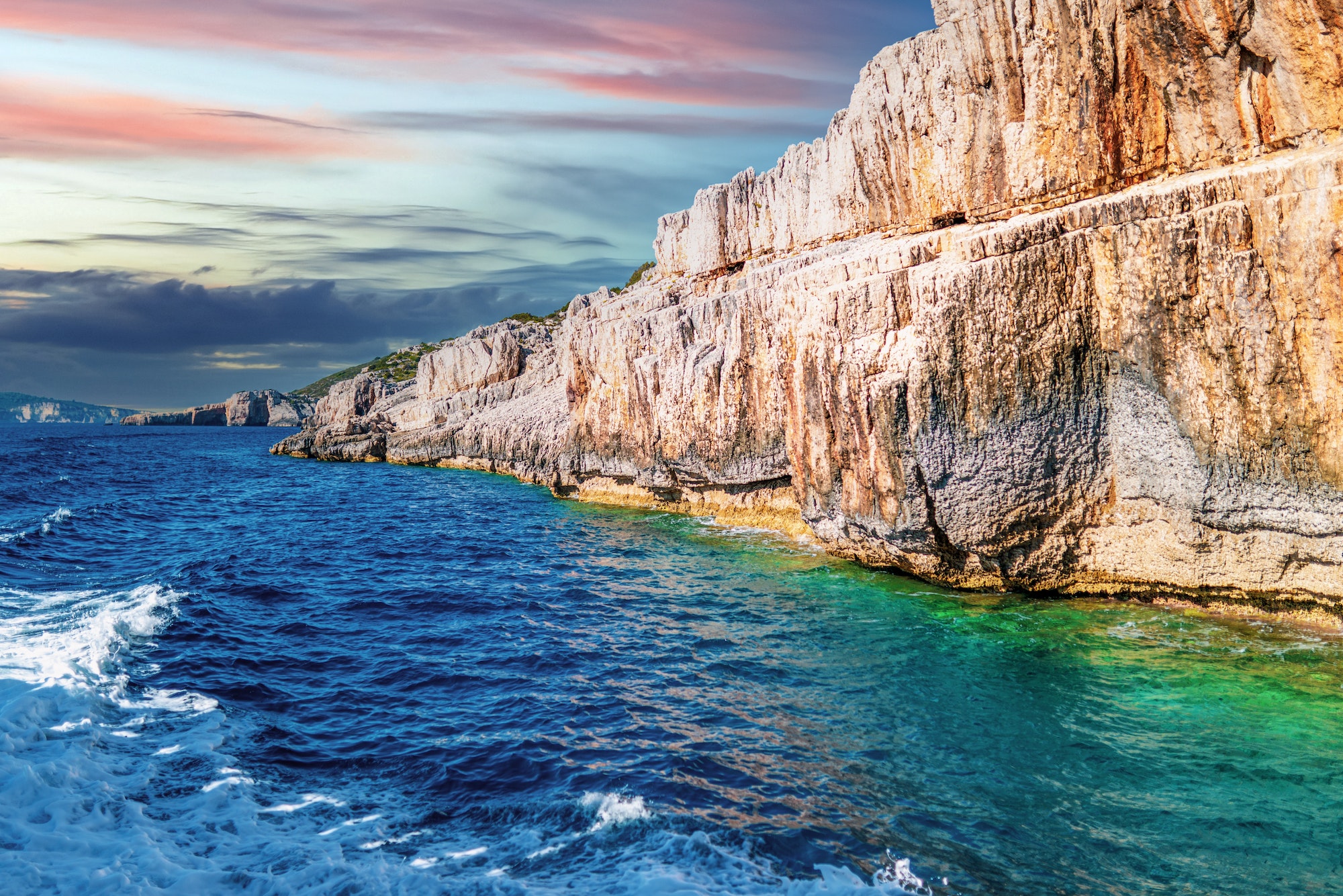 High stoned cliff on sea beach of Corfu island at sunset