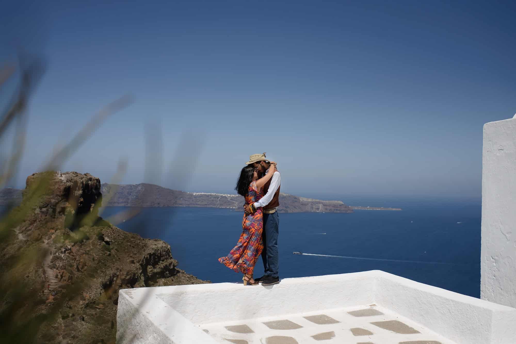 Young couple looks down on the landscape of the island of Santorini