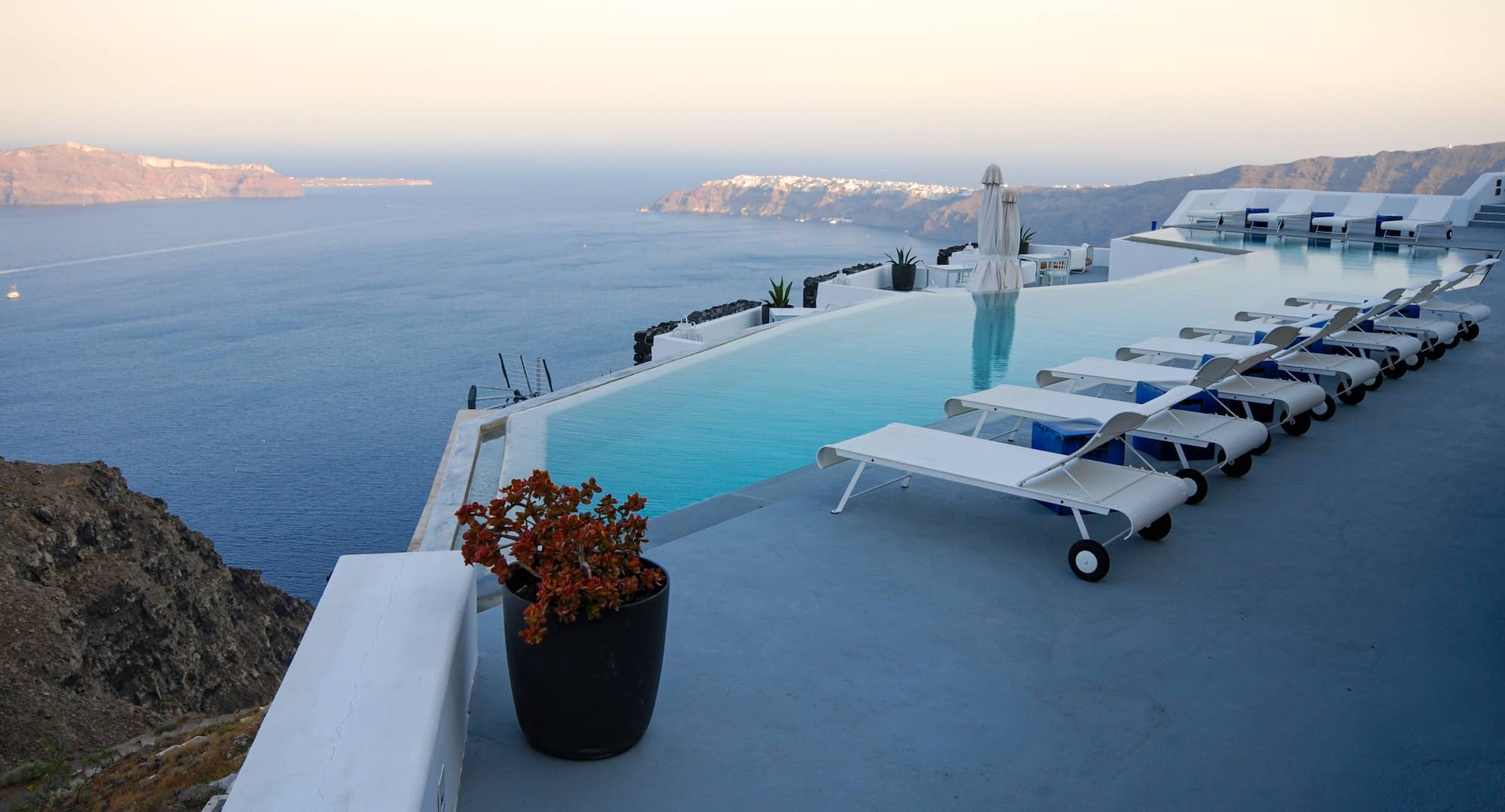 Roof garden of a holiday resort hotel against the ocean at sunset. Oia village, Santorini Island
